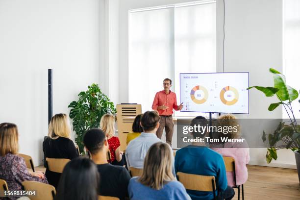 host giving presentation to small audience of participants - presents 20 years of giving stock pictures, royalty-free photos & images