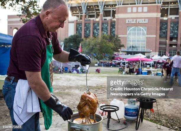 Texas A& fan Steve Boyd pulls a turkey from a frying pot while tailgating before an NCAA football game between Texas A& and LSU at Kyle Field on...