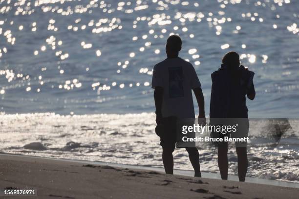 Visitors walk the beach at Smith Point County Park during the early morning hours on July 25, 2023 in Shirley, New York. Higher temperatures...