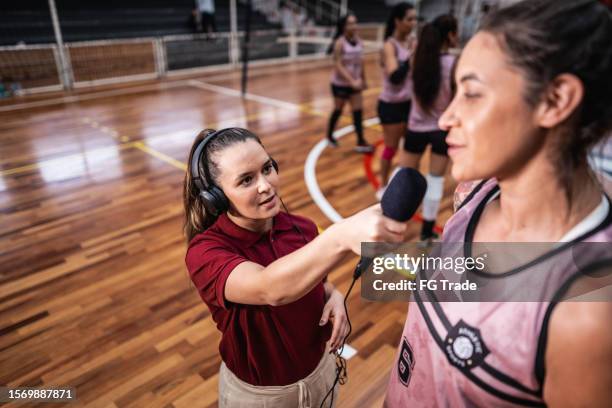 junge tv-reporterin interviewt volleyballspielerin auf dem sportplatz - fernsehreporter stock-fotos und bilder