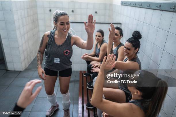 female volleyball team greeting with high-five in the locker room - pre game huddle stock pictures, royalty-free photos & images