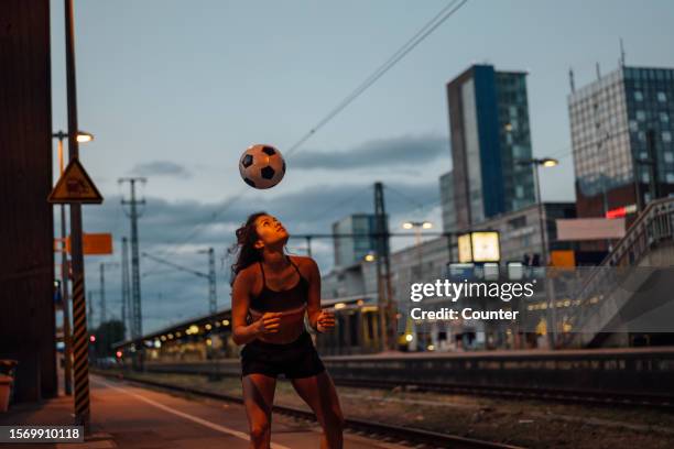 woman heading a soccer ball in city in evening - freiburg skyline stock pictures, royalty-free photos & images