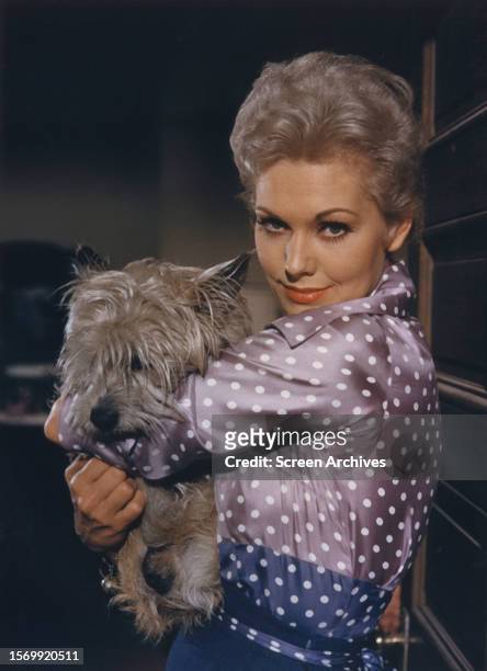 Kim Novak holding pet dog in a publicity portrait for the 1957 movie 'Pal Joey'.
