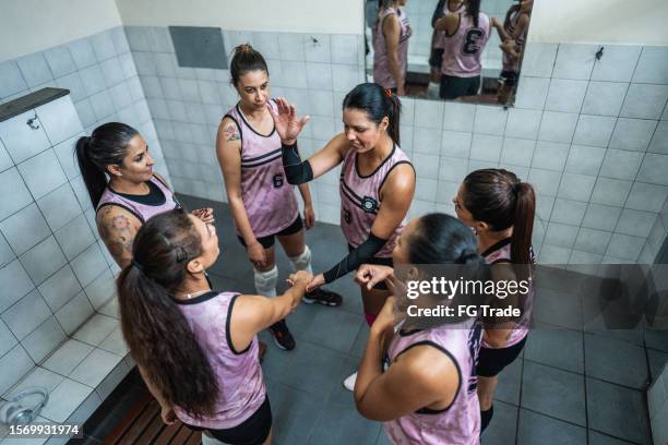 female volleyball team stacking hands before the game in the locker room - pre game huddle stock pictures, royalty-free photos & images