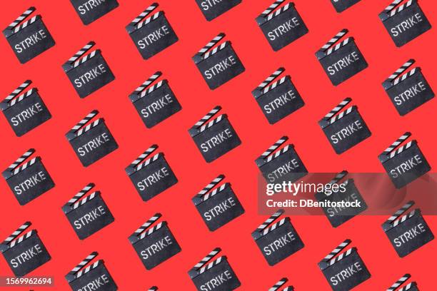 pattern of vintage wooden movie industry clapperboards with the word 'strike' written on it in chalk, on a red background. shooting, strike, actors, screenwriters, cinema, entertainment and hollywood. - film benefit stock pictures, royalty-free photos & images