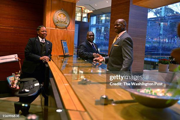 Jean Kabre, R, talks with co-workers Justine Osborne, L, and Daniel Ezoua, C, where Kabre works as a concierge and event planner at 101 Constitution...