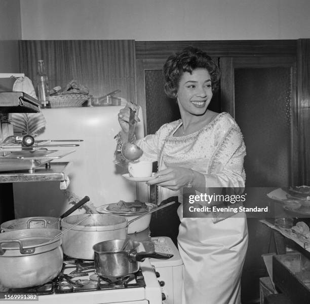 Welsh singer Shirley Bassey cooking in a kitchen, January 12th 1960.