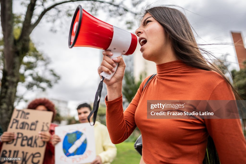 Adolescente gritando em megafone em protesto ambiental ao ar livre