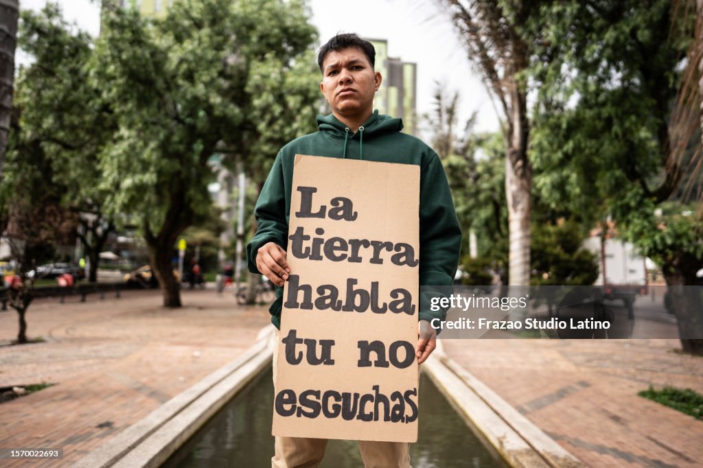 Retrato de un joven manifestante sosteniendo una pancarta sobre el medio ambiente al aire libre