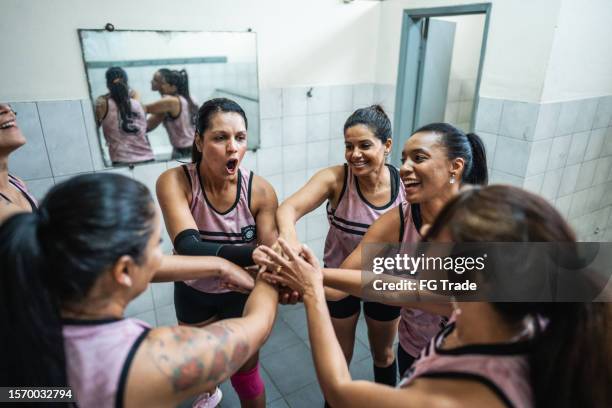 female volleyball team stacking hands before the game in the locker room - pre game huddle stock pictures, royalty-free photos & images