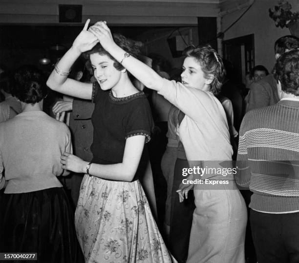 Two women jiving, one holding the other's hand as she twirls on the dancefloor of a cub in England, United Kingdom, circa 1955.