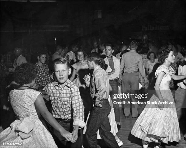 Groups of children and youths, with boys wearing checked shirts, square dancing on the dancefloor, United States, circa 1955.