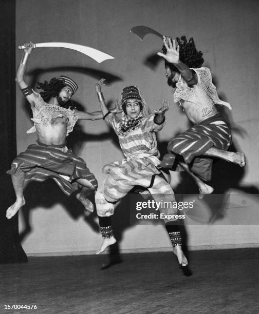 Three dancers, two wielding scimitars, leaping in costume, in a scene from an Inbal Dance Theater production at a theatre in Edinburgh, Scotland,...