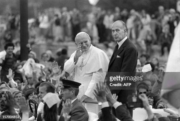 Pope John Paul II waves to the crowd next to French President Valery Giscard d'Estaing in Paris during his official visit in France on May 30, 1980.