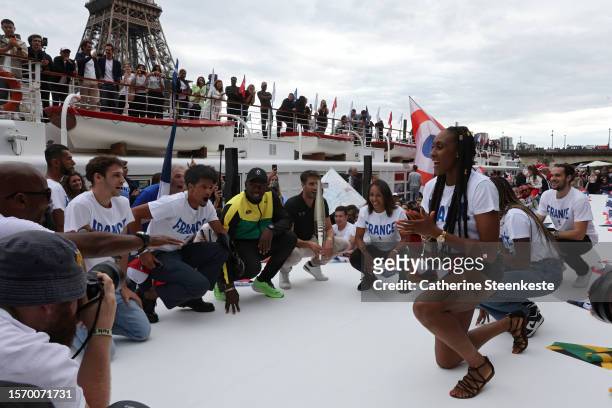Tony Estanguet, President of Paris 2024, and former sprinter Usain Bolt hold the Olympic torch during a Pre-Olympic tour along the Seine with the...