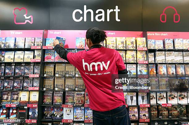 An employee arranges DVDs on a display inside a HMV pop-up store, in this arranged photograph in London, U.K., on Tuesday, Nov. 27, 2012. Fashion...