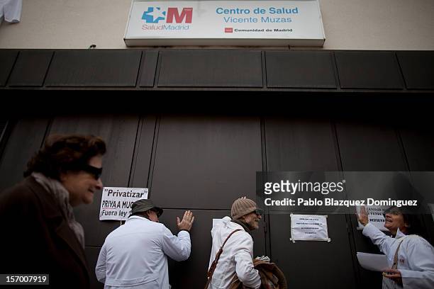 Health workers bang the door at the main entrance of Vicente Muzas Health Center while a woman arrives on November 27, 2012 in Madrid, Spain. For the...
