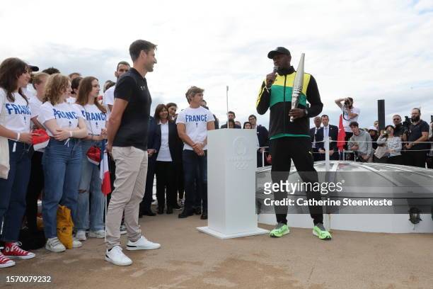 Tony Estanguet, President of Paris 2024 , and former sprinter Usain Bolt hold the Olympic torch during a Pre-Olympic tour along the Seine with the...