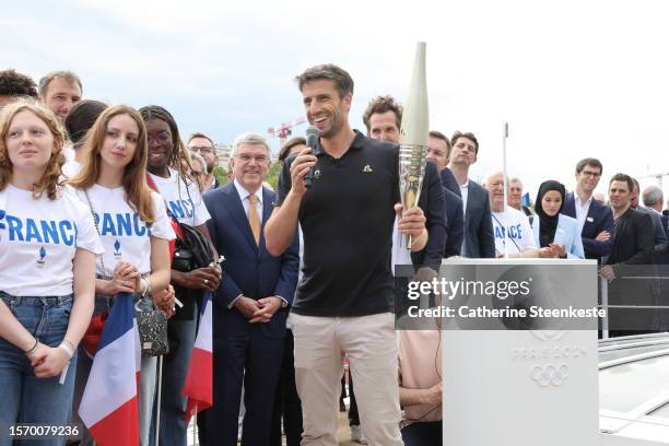 Tony Estanguet, President of Paris 2024, holds the Olympic torch during a Pre-Olympic tour along the Seine with the Eiffel Tower in the background on...