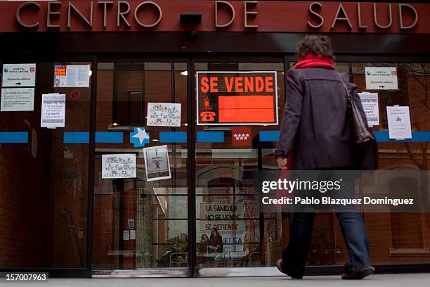 Woman enters at Goya Health Center while patients sit at the waiting room on November 27, 2012 in Madrid, Spain. Back banners read 'Health service is...