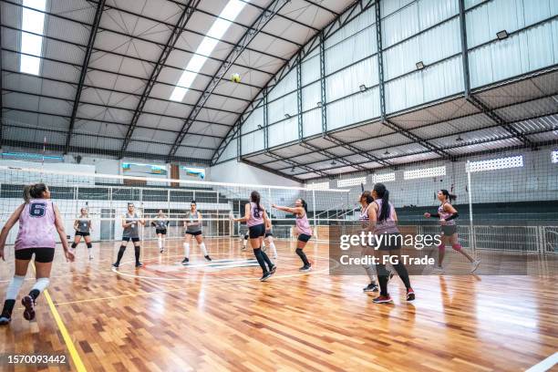 female volleyball players playing a volleyball match on the sports court - candid volleyball stock pictures, royalty-free photos & images