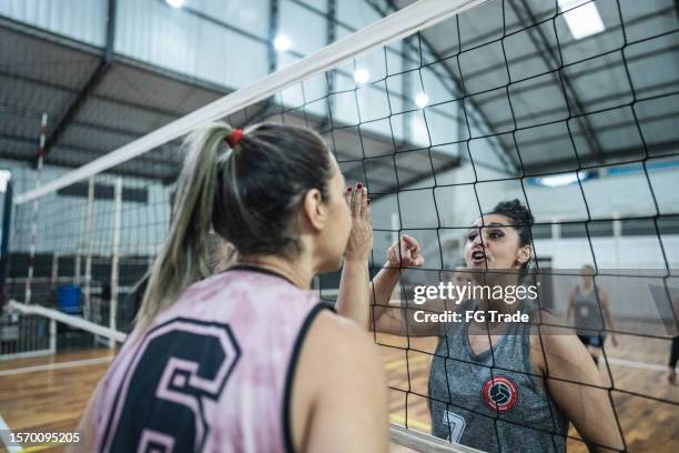 female volleyball player arguing with opposing team on the sports court - aanvallen sporten stockfoto's en -beelden