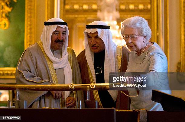 The Amir Sheikh Sabah Al-Ahmad Al-Jaber Al-Sabah of Kuwait and Queen Elizabeth II look at a gold sword that was presented to the Queen by Kuwait for...
