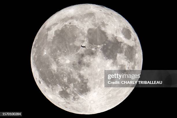 This photograph taken on August 1, 2023 from Toulouse, southern France, shows a Boeing 737 passenger aircraft in front of a full moon, flying from...