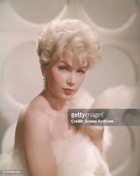 Stella Stevens poses bare-shouldered holding white fur against chest in a publicity portrait, circa 1963.