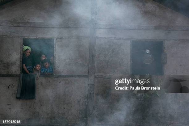 Rohingya look out from a window as smoke rises from people cooking over open fires at a school that is now a makeshift IDP camp November 24, 2012 on...