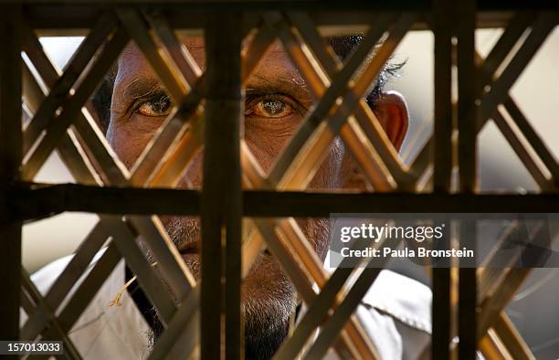Rohingya man peers into a makeshift mosque as families crowd a tented camp November 25, 2012 on the outskirts of Sittwe, Myanmar. An estimated...
