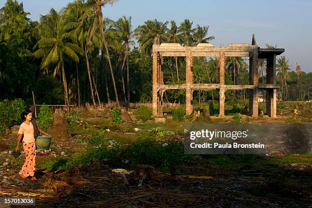 Woman walks past a burnt out area where dozens of families used to live until fires destroyed the homes November 25, 2012 Sittwe, Myanmar. An...