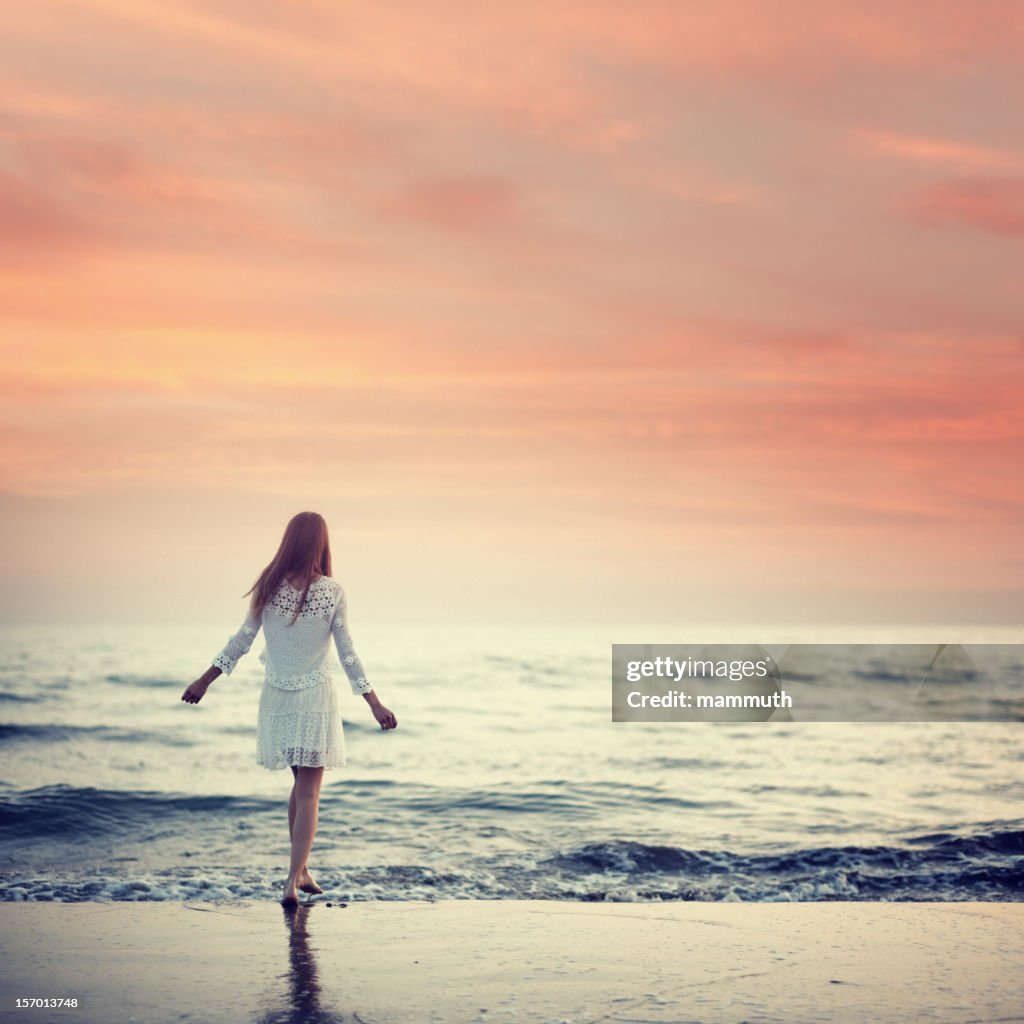 Mädchen zu Fuß am Strand bei Sonnenuntergang