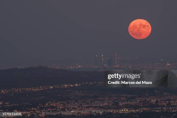 The full supermoon of August, known as the Sturgeon Moon, rises over the skyline with the skyscrapers of the Four Towers Business Area of Madrid.