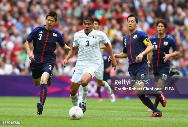 Carlos Salcido of Mexico is chased by Takahiro Ohgihara and Maya Yoshida of Japan during the Men's Football Semi Final match between Mexico and...