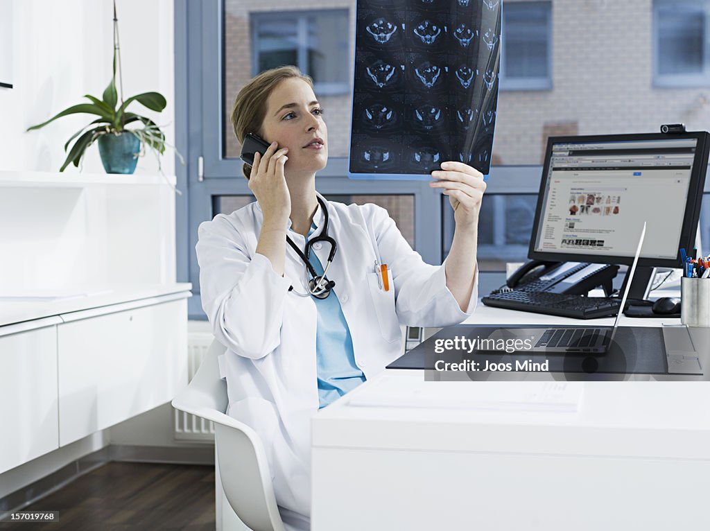 Doctor looking at x-ray`s,  using smart phone