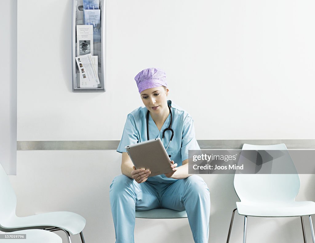 Feamle surgeon using digital tablet in waitng room