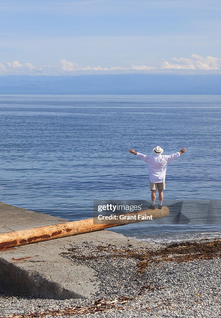 Man standing on a log at the beach