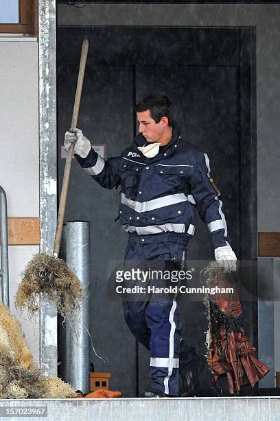 Police officer wearing a protective suit cleans parts of a Caritas employment facility for handicapped where a fire killed 14 people on November 27,...
