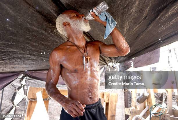 Rick White drinks water while cooling down in his tent in a section of the 'The Zone', Phoenix's largest homeless encampment, amid the city's worst...