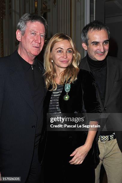 Emmanuelle Beart poses with Directors Regis Varnier and Olivier Assayas after being honored the Officier des Arts et des Lettres at Ministere de la...