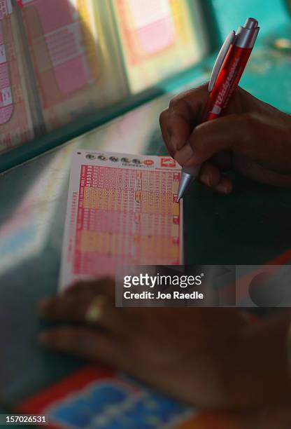 Debra Bea fills out her Powerball numbers as she buys tickets at Circle News Stand on November 27, 2012 in Hollywood, Florida. The jackpot for...