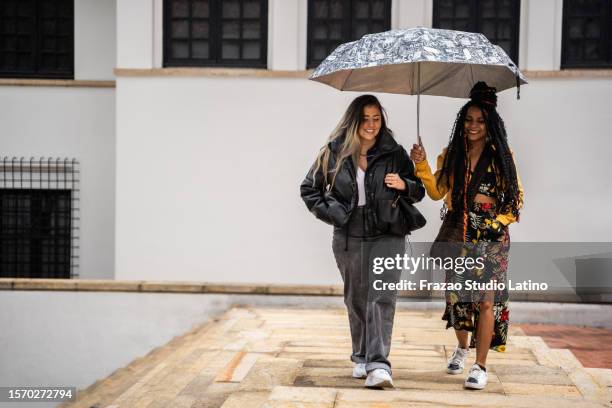 friends talking and walking while hold a umbrella in the city - la candelaria bogota stock pictures, royalty-free photos & images