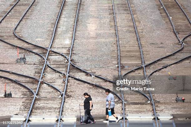 Person carries a water jug as people cross railroad tracks amid the city's worst heat wave on record on July 25, 2023 in Phoenix, Arizona. While...