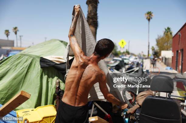 Homeless person adjusts a friend's tent to help increase shade cover in a section of the 'The Zone', Phoenix's largest homeless encampment, amid the...