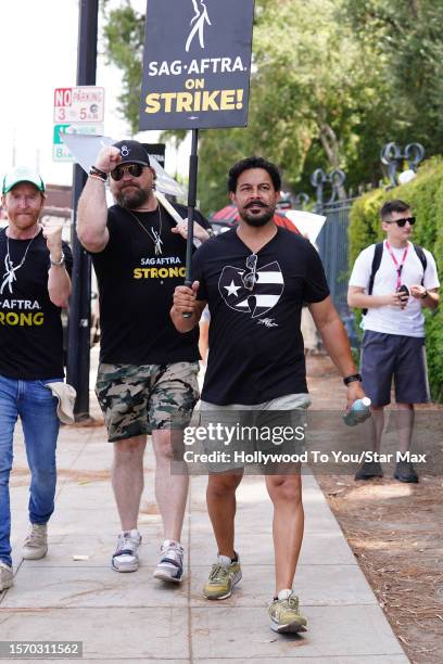 Tony Curran and Jon Huertas walk the picket line in support of the SAG-AFTRA and WGA strike on August 1, 2023 in Burbank, California.