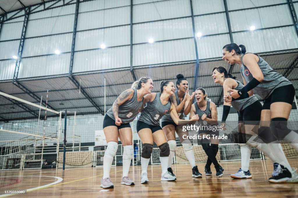 Female volleyball team celebrating after win a match on the sports court