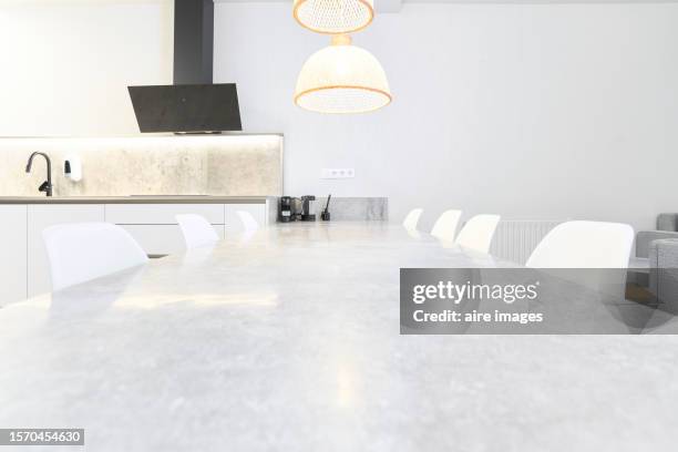 front view of a dining table with white chairs, two hanging lamps, part of the kitchen, dishwasher faucet, white wall backgrounds - dishwasher front stockfoto's en -beelden