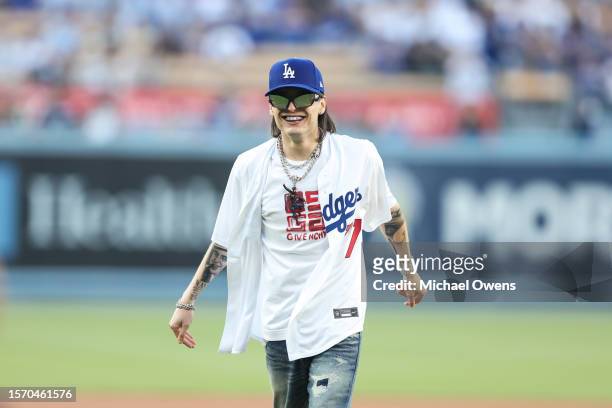 Rapper Peso Pluma reacts after throwing the first pitch prior to a game between the Los Angeles Dodgers and the Pittsburgh Pirates at Dodger Stadium...