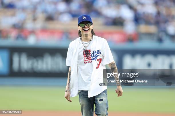 Rapper Peso Pluma reacts after throwing the first pitch prior to a game between the Los Angeles Dodgers and the Pittsburgh Pirates at Dodger Stadium...